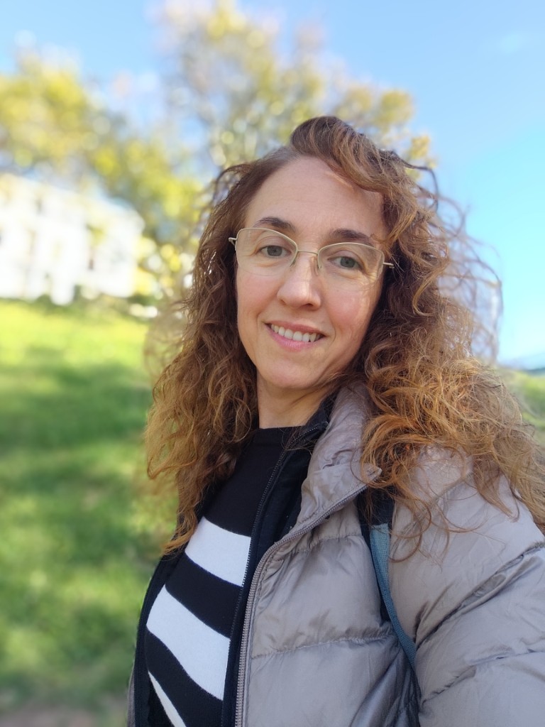 retrato de carolina pérez una mujer sonriente de mediana edad con melena rizada paseando por la calle